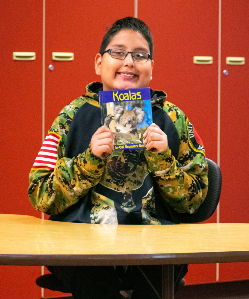 A photo of Mahto, showing off one of his favorite books he likes to read.