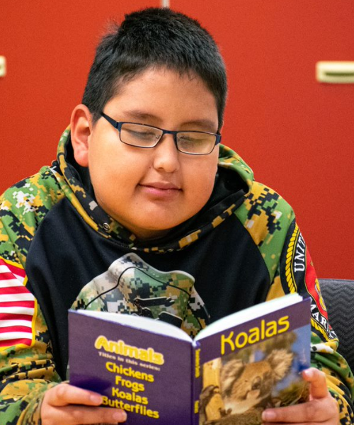 A photo of Mahto, smiling, and reading his book about koalas